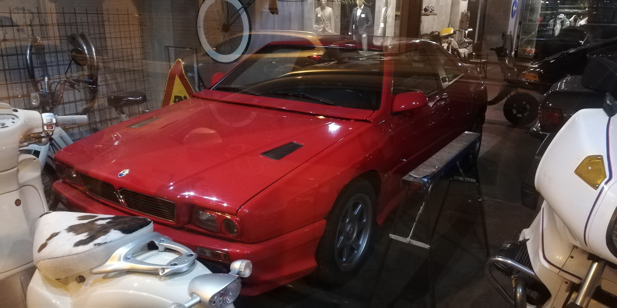 Auto sportiva rossa e scooter d’epoca nell’officina